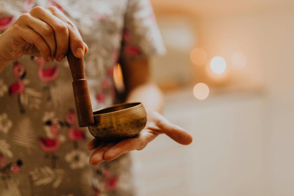 Close-up of a person using a singing bowl for meditation, promoting relaxation and wellness.